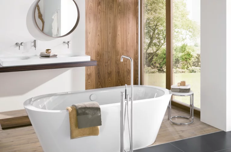 Bañera ovalada exenta de acero vitrificado, delante lavabo rectangular sobre encimera.
